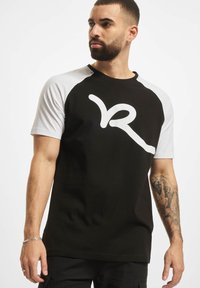 Juoda ir balta trumpa rankovė t-shirt su apvaliu kaklu, su dideliu baltu logotipu priekyje ir kontrastingomis raglan rankovėmis.