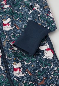 Marineblå børneheldragt med Moomin-figurer, grønne blade, hvide prikker og en rød detalje på kraven. Blødt bomuldsstof.