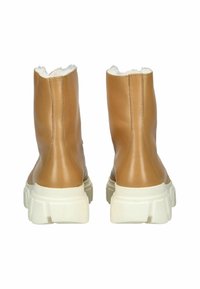 Botas de cuero marrón hasta el tobillo con suela gruesa blanca, que cuentan con un suave forro interior y un diseño limpio y liso sin patrones adicionales.