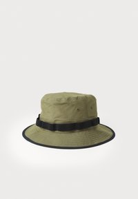 Green bucket hat made of fabric with a black band and edging. Features ventilation eyelets and a soft texture.