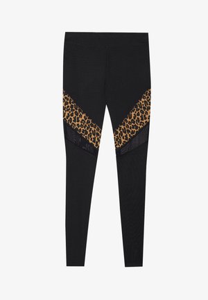 Melni legingi ar leopardu rakstu paneļiem, kas izveidoti chevron dizainā. Ievērojama tekstūrēta auduma, kontrastējošas raksts un elastīga josta.
