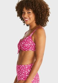 Rosa blommig bikini-set som består av en bralette med en rosett och högmidjade bottoms, tillverkat av mjukt, texturerat tyg.