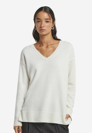 V-Ausschnitt, langärmliger Pullover aus weichem weißen Material. Mit geripptem Saum und Bündchen, entspannter Passform und feiner Textur.