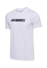 Hvid bomulds t-shirt med korte ærmer, der har et fremtrædende sort "HUMMEL" logo på brystet. Glat tekstur og klassisk pasform.