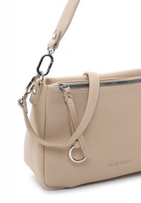 Sac à main en cuir beige avec surface texturée, quincaillerie argentée, fermeture éclair et une bandoulière amovible. Présente un accent en forme d'anneau.