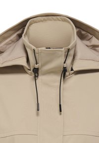 Beige jacka med hög krage, med kontrasterande svarta detaljer och dragskojusteringar, tillverkad av ett slätt, lätt material.