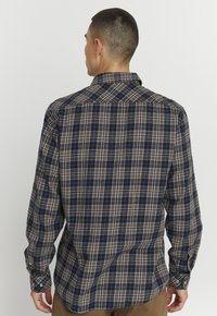 Herren Langarmhemd in marineblau, braun und cremefarbenem Karomuster. Mit Button-Down-Kragen und Ein-Knopf-Manschetten. Aus Baumwolle.