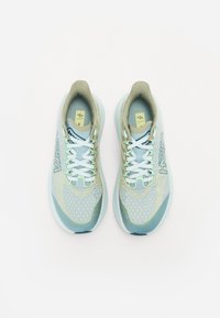 Baskets de sport bleu clair et vert avec une tige en mesh, des accents contrastés, une semelle rembourrée et des lacets plats. Détails réfléchissants partout.