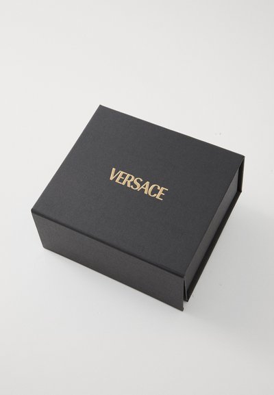 Svart, rektangulær boks med teksturert overflate, med en gull "VERSACE"-logo på toppen. Kompakt design, egnet for emballasje.
