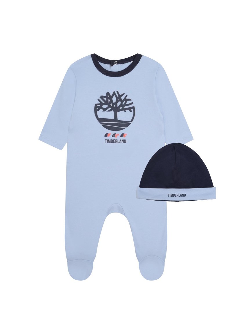 Un body pour bébé bleu clair à manches longues, avec un emblème d'arbre noir et le texte "TIMBERLAND". Inclus un bonnet marine assorti avec une bande bleue.