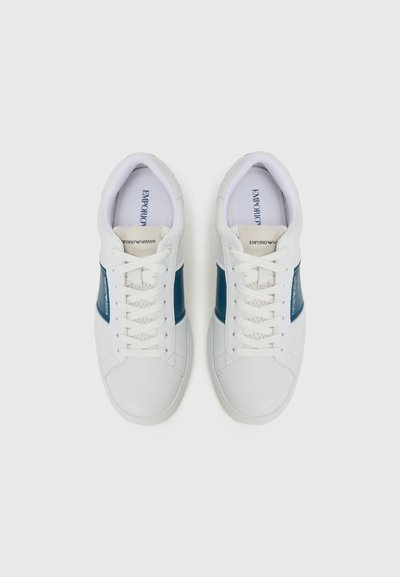 Vita sneakers med ett blått läderband, snördesign, texturerad gummisula och präglad logotyp på tungan. Slät ovansida.