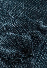 Tume sinine pehme visketepp rug kainete ribadekujuliste mustritega, millel on pehme, paks kangas ja mugav väljanägemine.