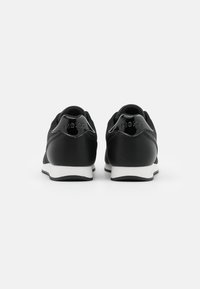 Svarta sneakers med en blandad materialdesign, slät läderfinish, kontrasterande vit sula och blanka detaljer på hälen.