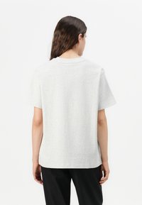 T-shirt en coton gris avec un col rond et des manches courtes. Caractéristiques d'une coupe décontractée et de coutures à plat. Aucun motif ni accent visible.