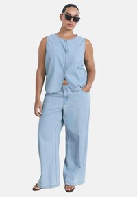 Light blue denim two-piece outfit featuring a sleeveless button-up top and wide-leg pants, showcasing a relaxed fit and smooth texture.