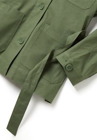 Giacca verde oliva in cotone con una texture liscia, dotata di due tasche anteriori sul petto, chiusura con bottoni e cintura in vita da annodare.