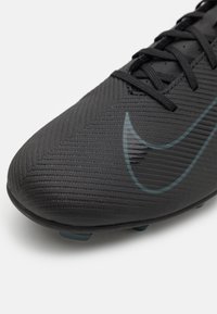 Mustat jalkapallosukat, joissa on kohokuvioitu pinta, ja joissa on näkyvä musta Nike-logotyyppi ja mustat nauhat. Suunniteltu tarjoamaan optimaalinen pito nurmella.