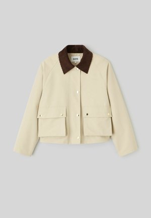 Veste courte beige avec col en velours côtelé marron, boutons-pression à l'avant et deux grandes poches à rabat avec fermeture par bouton-pression.