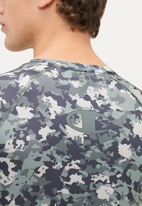 Herreshirt til sport i camouflage-mønster i grå, blå og hvid. Har en glat tekstur, rund halsudskæring og logo på ryggen.