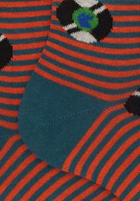 Calze a righe nei colori arancione e teal con un motivo in bianco e nero, che rappresenta un globo in un design circolare. Morbido, in texture a maglia.