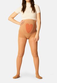 Collant beige modellante con un design a cuore integrato in una tonalità contrastante. Il tessuto è liscio e semitrasparente, offrendo supporto.