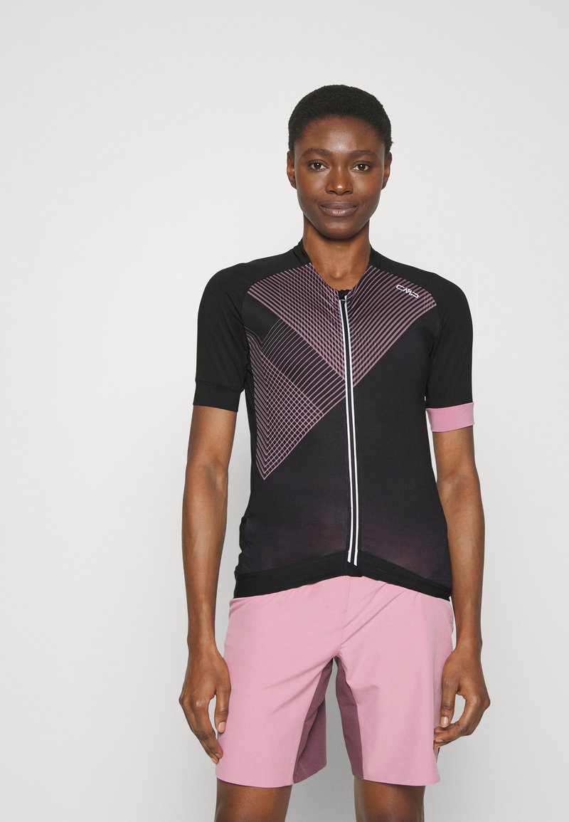 Schwarzes Fahrradtrikot mit pinkem geometrischem Muster, kurzen Ärmeln, frontalem Reißverschluss und weicher Textur. Kombiniert mit hellroten Shorts.