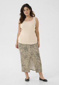 Beige gerippter Tank-Top in Kombination mit einem Rock im Leopardenmuster, der einen Schlitz vorne hat; schwarze Ballerinas runden das Outfit ab.