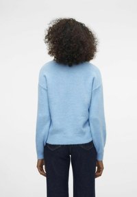 Light blue, wool blend sweater with a round neckline and dropped shoulders, featuring a ribbed hem. Paired with dark denim pants.