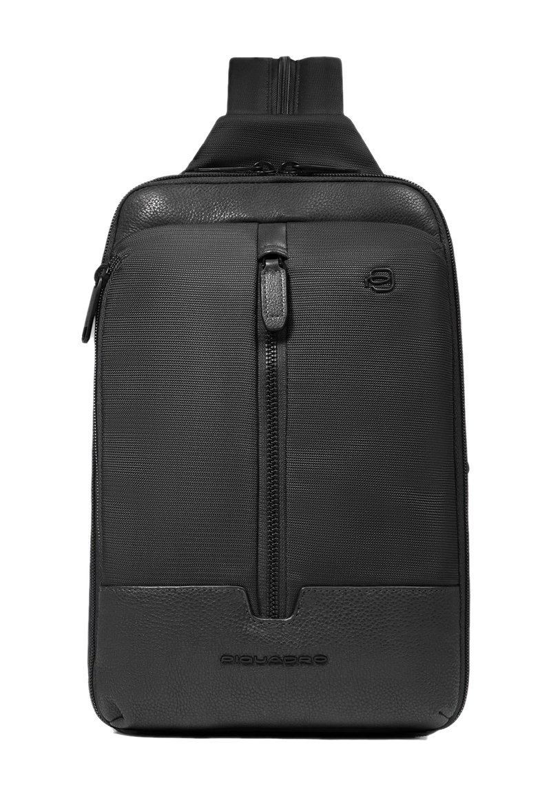 Zwarte rugzak gemaakt van een mix van gestructureerde stof en glad leer. Voorzien van een ritsvak aan de voorkant en een handvat bovenop om te dragen.