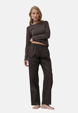Langärmliges dunkelbraunes Oberteil, kombiniert mit gestreiften braunen Schlafanzughosen. Die Hosen besitzen einen elastischen Bund und einen Knopfdetails.