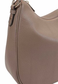 Tan leren handtas met een gestructureerd oppervlak, gebogen vorm, goudkleurige hardware en een zijritssluiting.