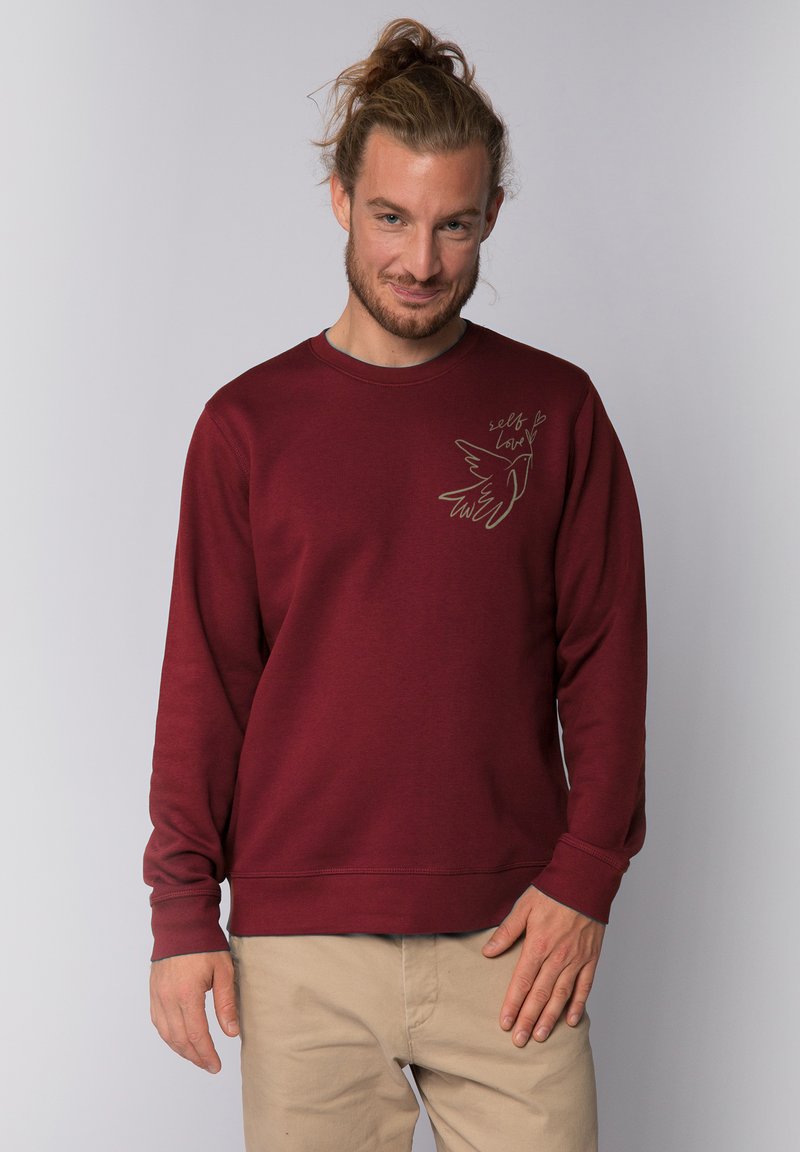 Maroon sweatshirt with crew neck, long sleeves, and a fitted hem. Features a bird illustration and the text "self love" in a subtle design.