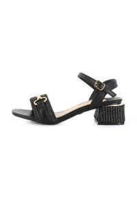 Sandalia negra con una cinta ancha de textura trenzada y una hebilla dorada. Tacón corto de bloque con una superficie texturizada. Correa ajustable en el tobillo.