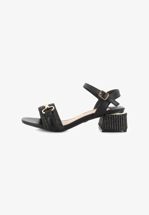 Sandalia negra con una cinta ancha de textura trenzada y una hebilla dorada. Tacón corto de bloque con una superficie texturizada. Correa ajustable en el tobillo.