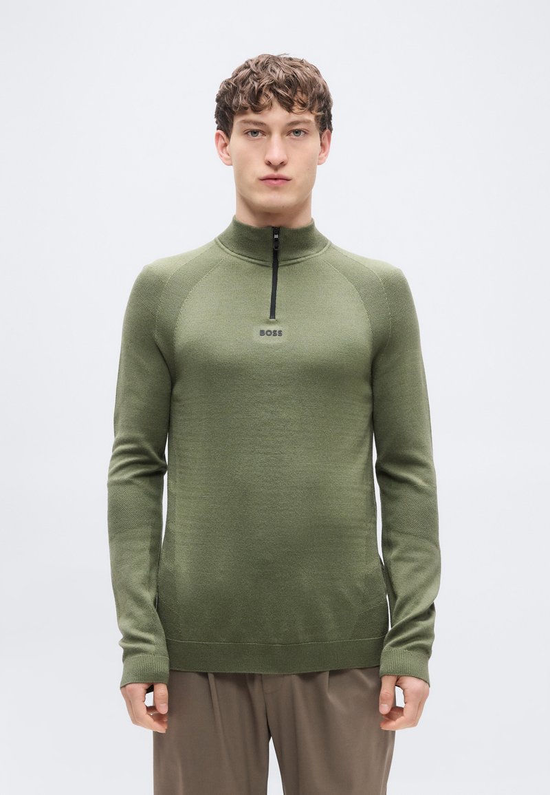 Πράσινο, εφαρμοστό πουλόβερ με φερμουάρ στον λαιμό, ραβδωτά μανίκια και σταθερή υφή. Διαθέτει μικρό λογότυπο "BOSS" στο στήθος.