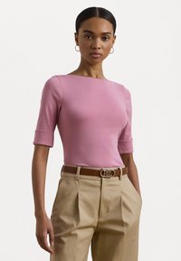 Top justo rosa com mangas curtas, decote redondo e textura suave. Combinado com calças de cintura alta beje e um cinto castanho com fivela de logotipo.