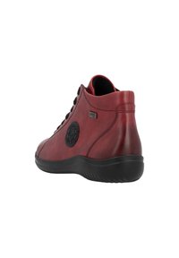 Bottine en cuir rouge avec des accents noirs, surface texturée, design courbé, bout arrondi et lacets à l'avant. Semelle en caoutchouc noire.