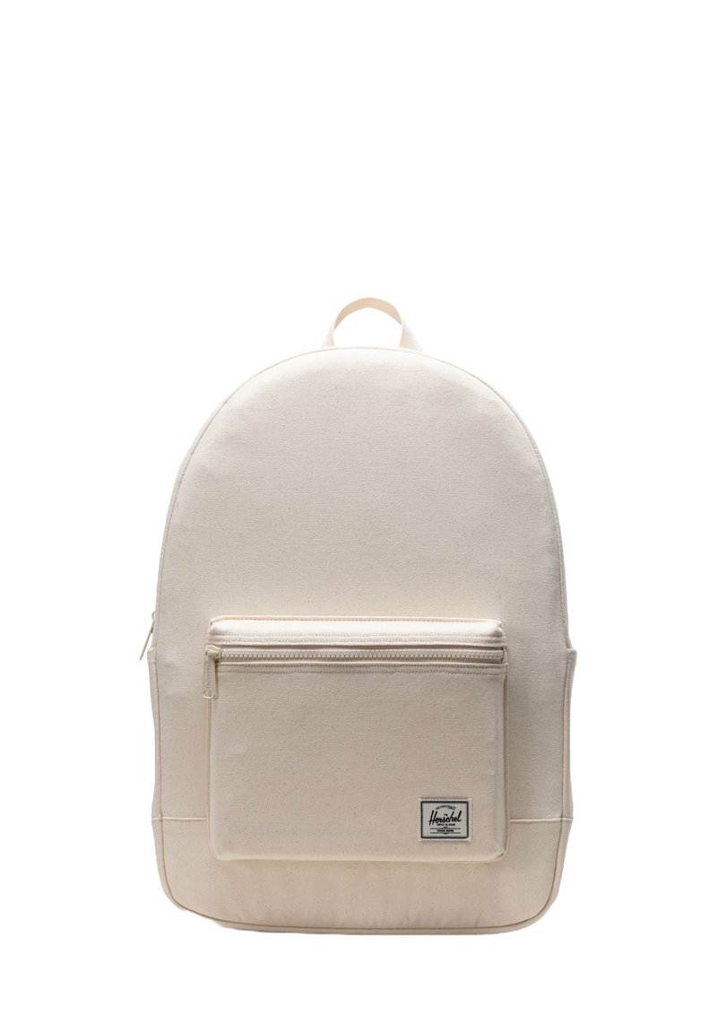Beige canvas backpack with a rounded top, a front zip pocket, and a logo patch at the bottom. Sturdy fabric and adjustable straps.