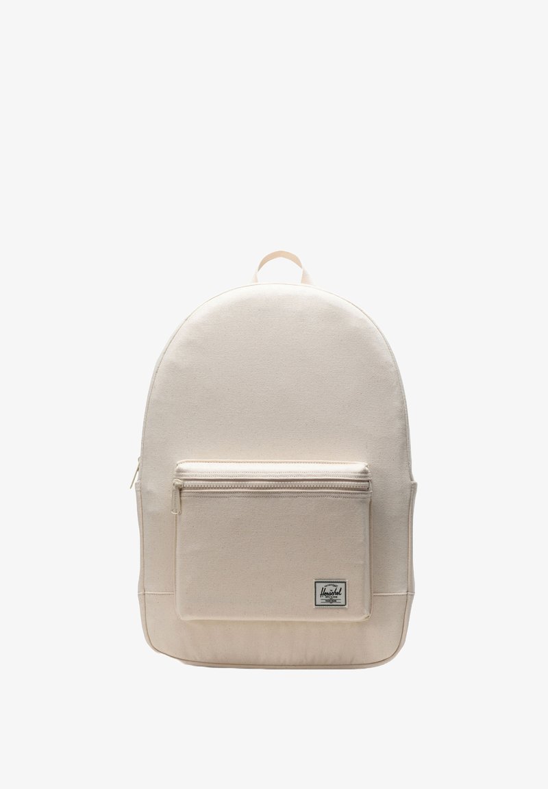 Beżowy plecak z płótna o zaokrąglonym wierzchu, z przednią kieszenią na zamek i naszywką z logo na dole. Solidny materiał i regulowane paski.
