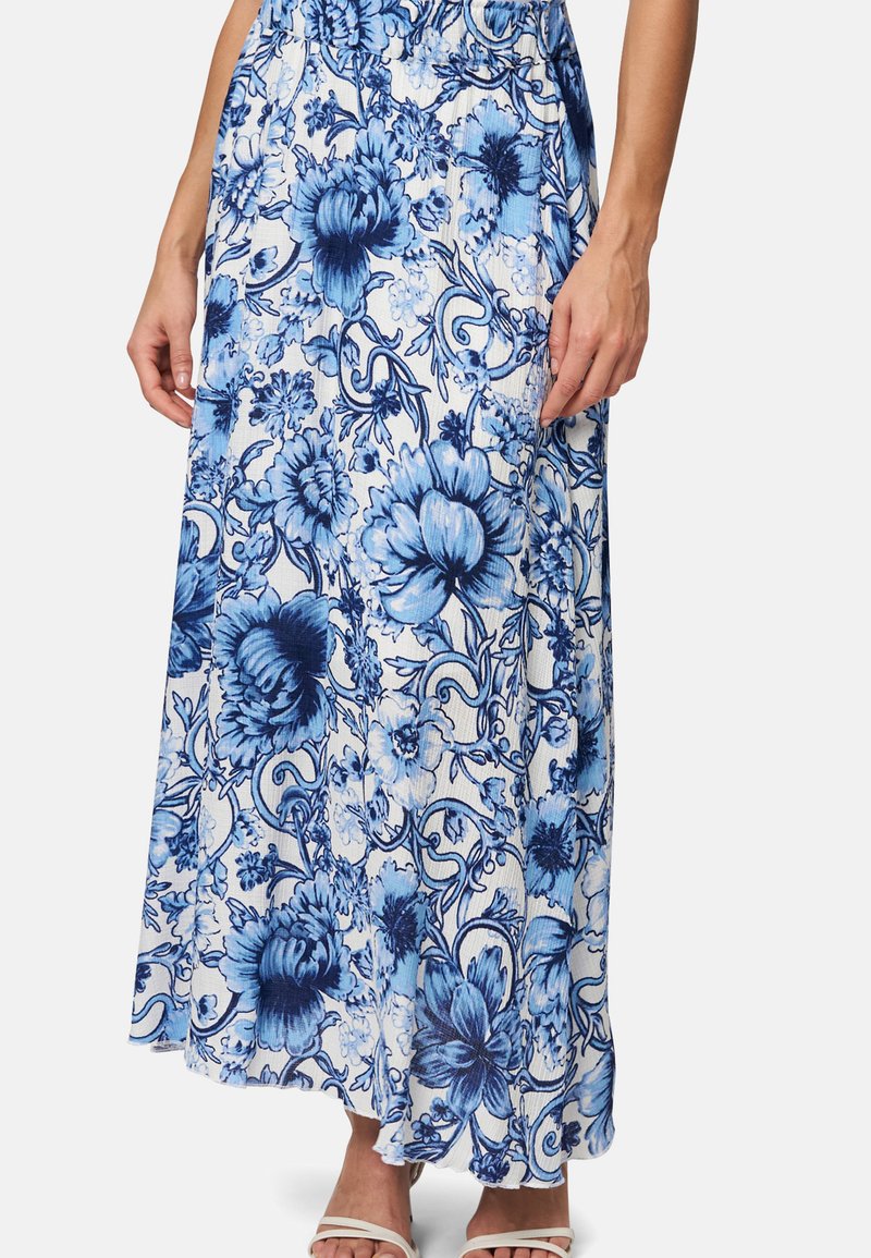 Jupe maxi florale dans des nuances de bleu et de blanc, dotée d'un tissu texturé, d'une taille élastique et de motifs floraux intricats tout au long.