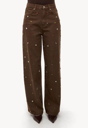 Bruine wijde jeans met verspreide embellissementen in verschillende vormen en kleuren, voorzien van een klassieke riemlus en een vijf-pocket ontwerp.