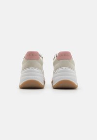 Baskets chunky avec une palette de couleurs beige et blanche, un onglet de talon rose, des accents en daim texturé et une semelle en caoutchouc striée.