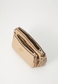 Beige syntetisk lærveske med to glidelåslommer, detaljer i gull, og en avtakbar kjedehank. Glatt tekstur.