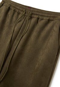 Olivengrüne Sweatpants mit elastischem Taillenbund und verstellbarem Kordelzug; weicher, strukturierter Stoff mit dezentem Glanz.