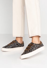 Šedé tenisky s leopardím potiskem a hnědými akcenty, s texturovaným svrškem, třemi suchými zipy a bílou gumovou podrážkou.