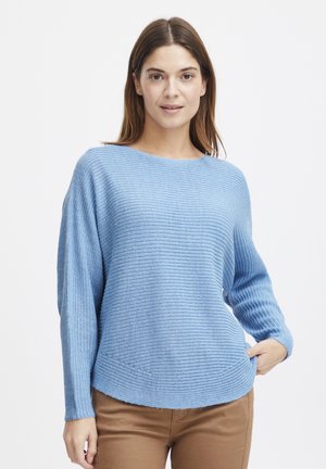 Light blue knit sweater with a loose fit, boat neckline, ribbed cuffs, and horizontal stripes, paired with brown trousers.