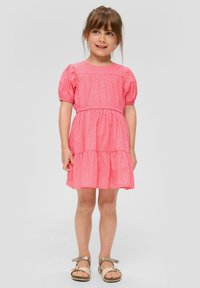 Rosa kurzärmliges Kleid mit strukturierten Punkten, gerafftem Taillenbereich und gestuftem Rock. Getragen mit hellbraunen Sandalen mit einer Schleifen-Detail.