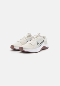 Scarpe da atletica di un beige chiaro con tomaia in rete, zona intermedia bianca e suola texturizzata color marsala. Presentano il logo swoosh nero e un design con lacci.