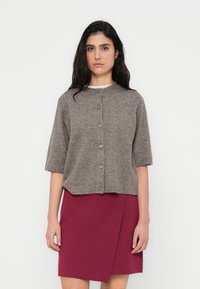Γκρι πλεκτή ζακέτα με κοντά μανίκια, στρογγυλή λαιμόκοψη και έξι κουμπιά. Συνδυάζεται με μπορντό φούστα τύπου wrap. Λεία υφή, καθημερινό σχέδιο.