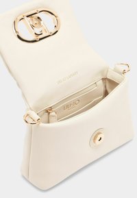 Kleine, cremefarbene Handtasche mit glatter Oberfläche, goldenen Beschlägen, Druckverschluss und einem Innenfach mit Kartenfächern.